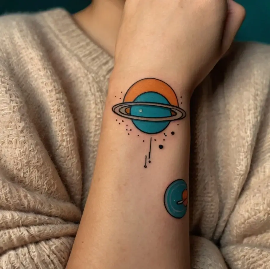 Colorful geometric planet tattoo with teal and orange hues, featuring rings and abstract dots on the forearm.