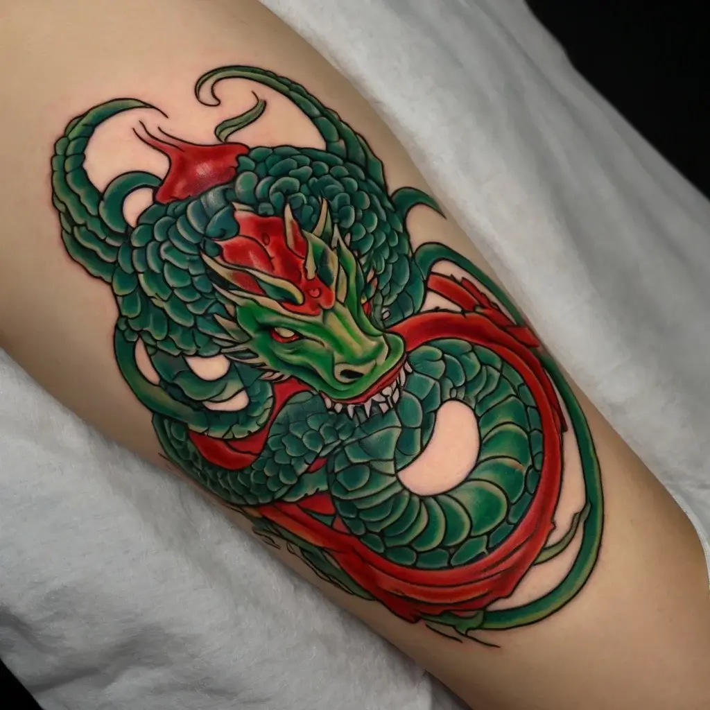 A vibrant tattoo of a green and red dragon with detailed scales and horns, coiling elegantly on an arm.