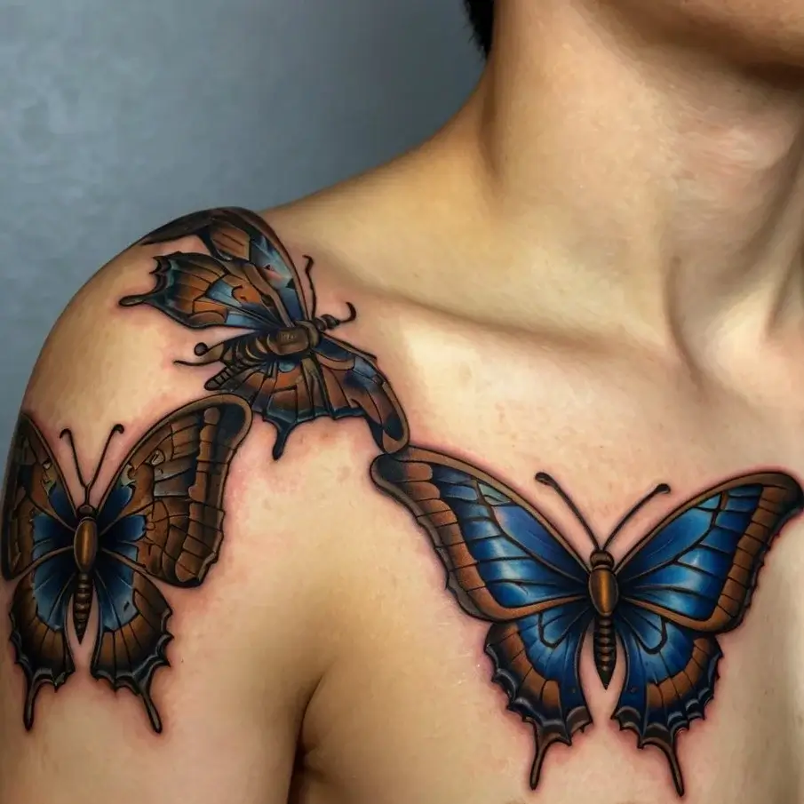 Three realistic blue and brown butterflies tattooed on the shoulder and collarbone, showcasing vibrant detail and shading.