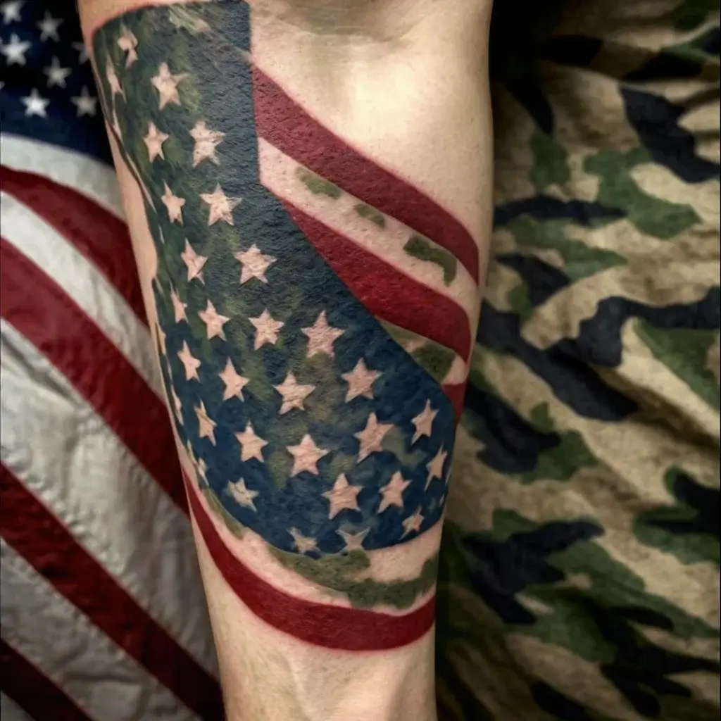 Tattoo of a tattered American flag wrapped around an arm, showcasing stars and stripes with a textured, weathered look.