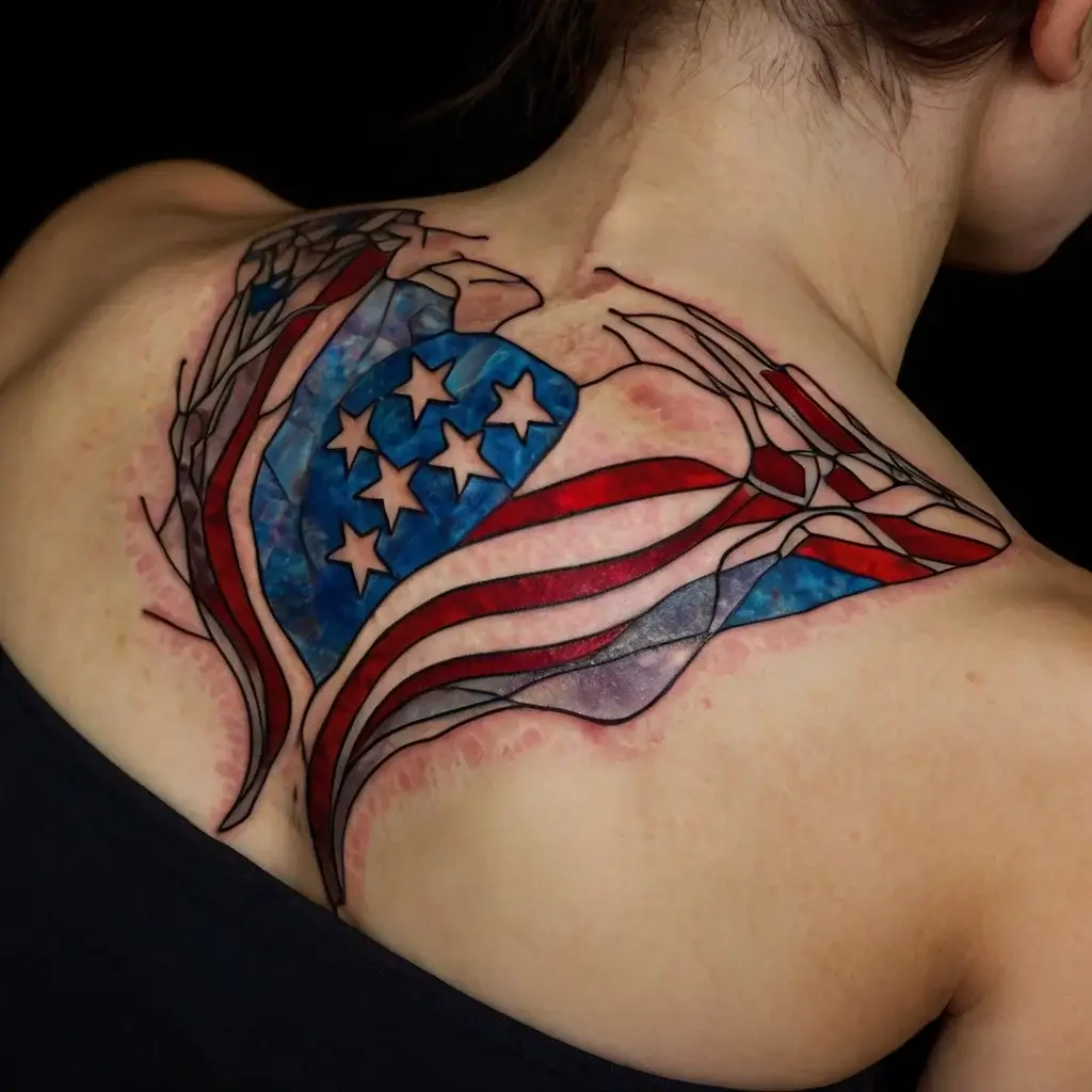 Tattoo of a stylized American flag, featuring a heart in stained-glass style, spread across the back and shoulders.