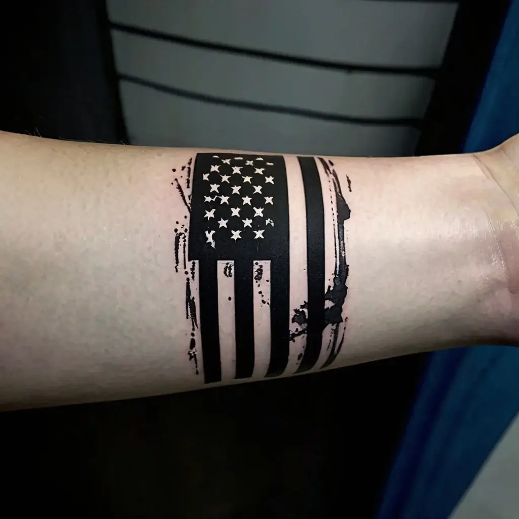 Tattoo of a weathered American flag with distressed, bold lines and stars, creating a vintage and rugged look on the forearm.