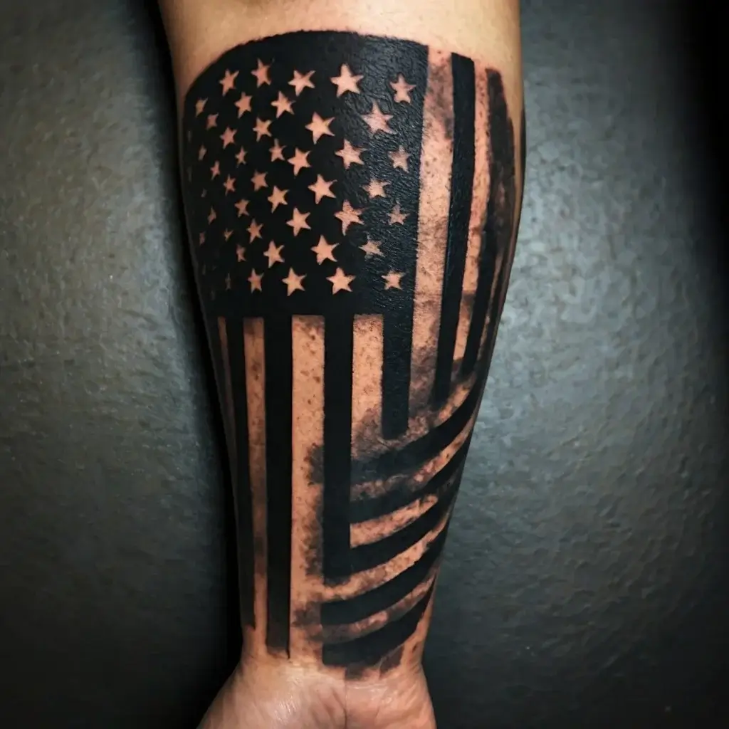 American flag tattoo in black ink with bold stars and stripes, creating a dynamic waving effect on the forearm.