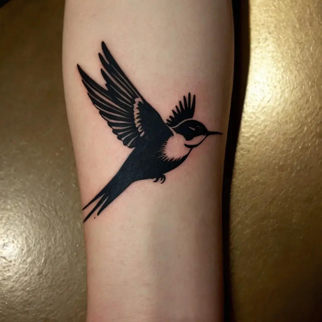 Bold black tattoo of a flying swallow on skin; its wings open wide, symbolizing freedom and new beginnings.