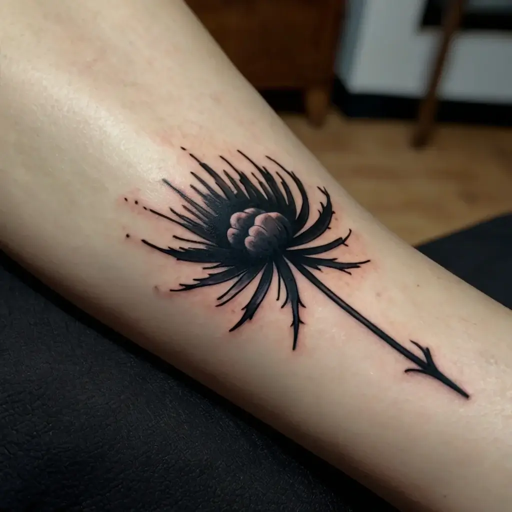 Black and gray dandelion tattoo with dynamic lines and a realistic touch, capturing a sense of movement and elegance.