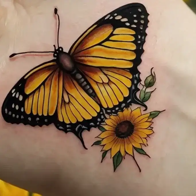 Butterfly and sunflower tattoo on forearm; vibrant yellow tones with detailed shadowing and leaves symbolize transformation.