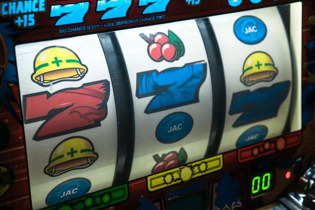A colorful slot machine tattoo with cherries, blue sevens, a hard hat, red flames, embodying luck and chance.